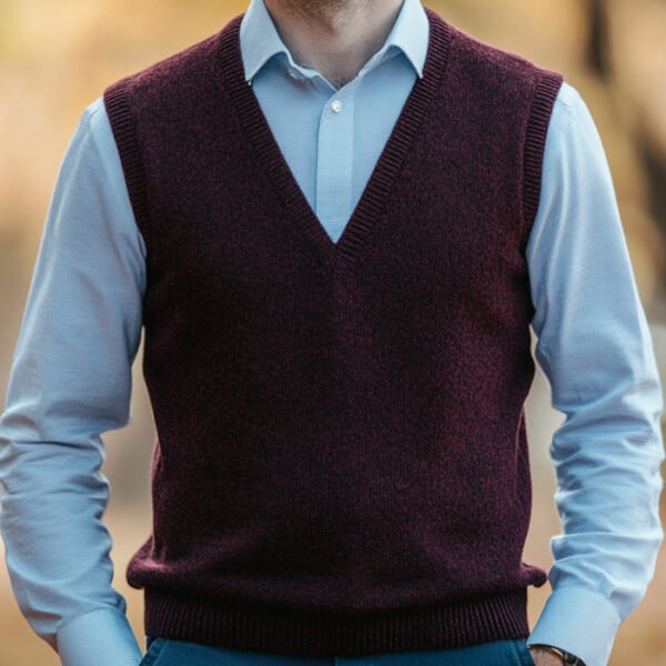 man wearing a dark red wool sweater vest over a light blue shirt